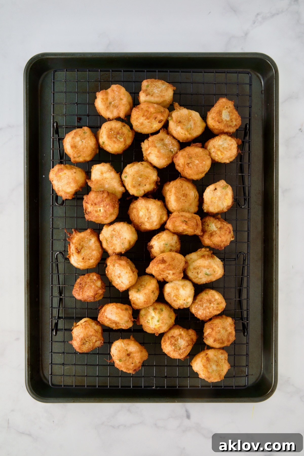 Fried squash puppies on wire rack set over a rimmed sheet pan.