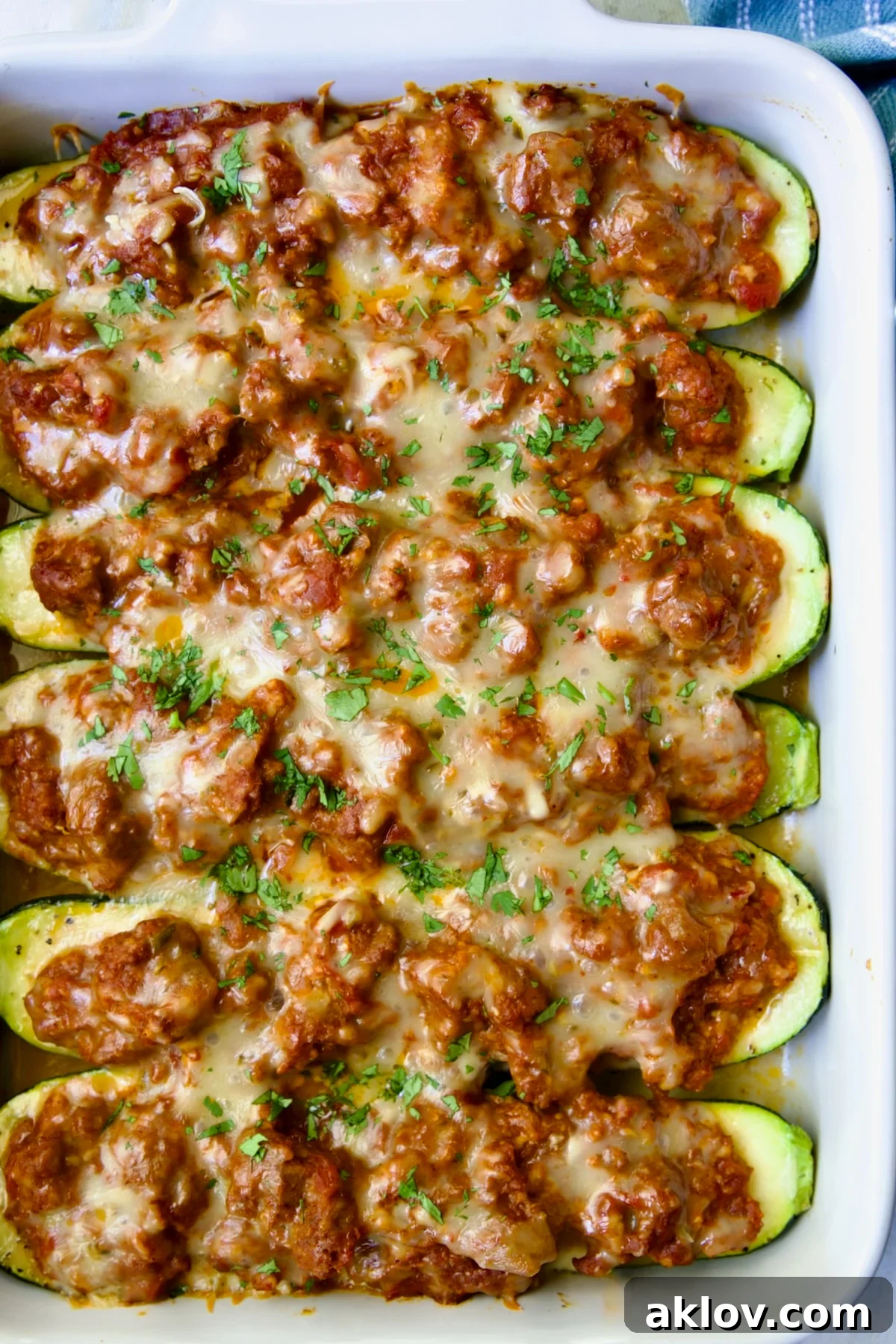 Six baked Chorizo-Stuffed Zucchini in white rectangular baking dish.