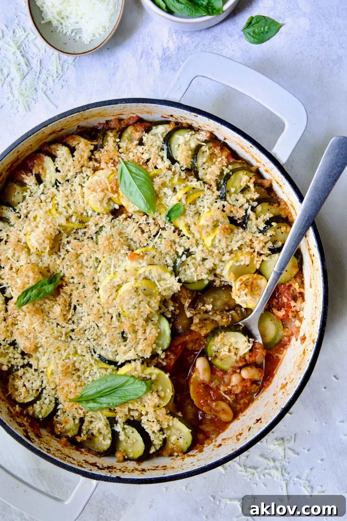 Summer Vegetable Cassoulet in white enamel cast iron skillet with serving spoon scooping some up.
