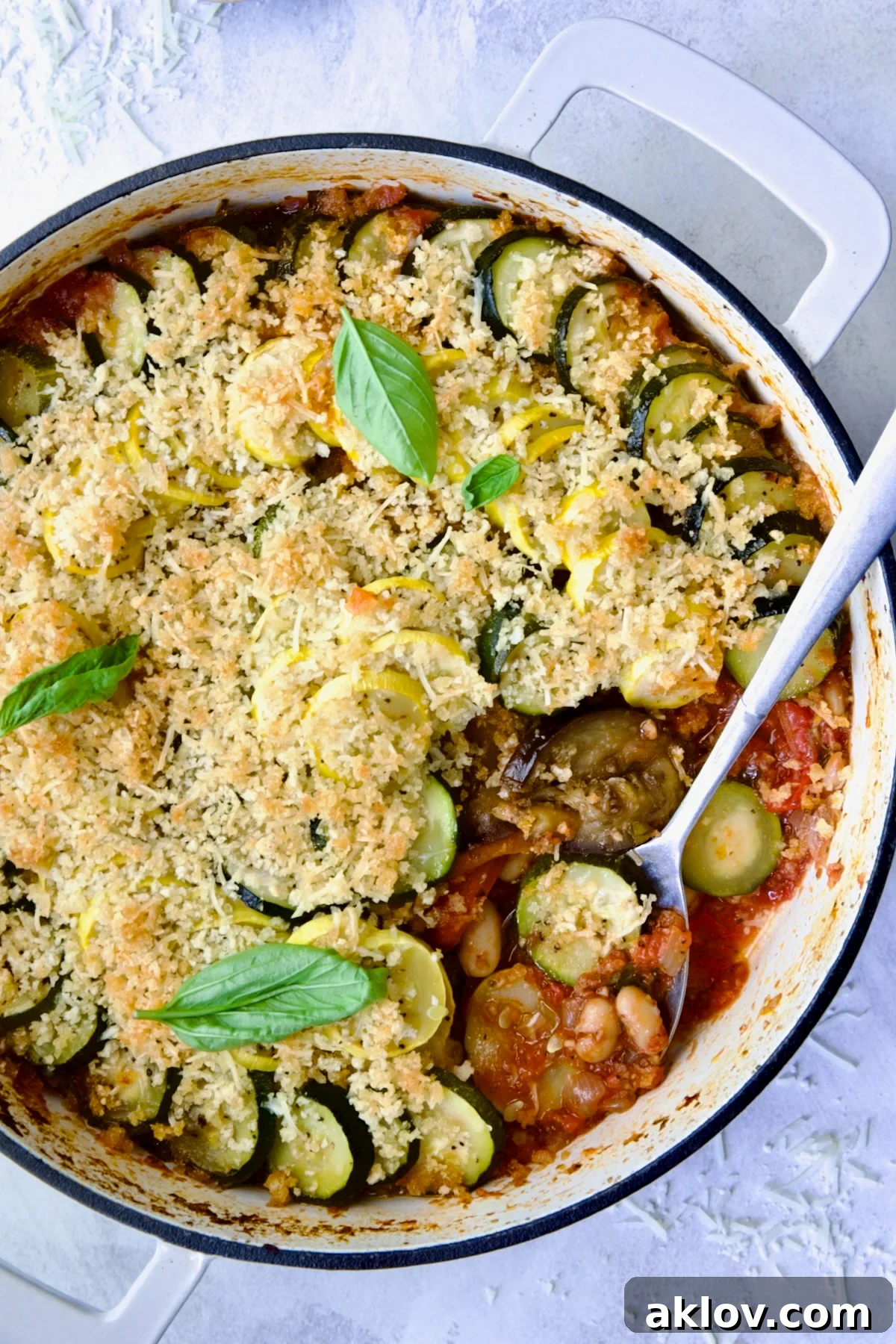 Summer Vegetable Cassoulet in white enamel cast iron skillet with serving spoon scooping some up.