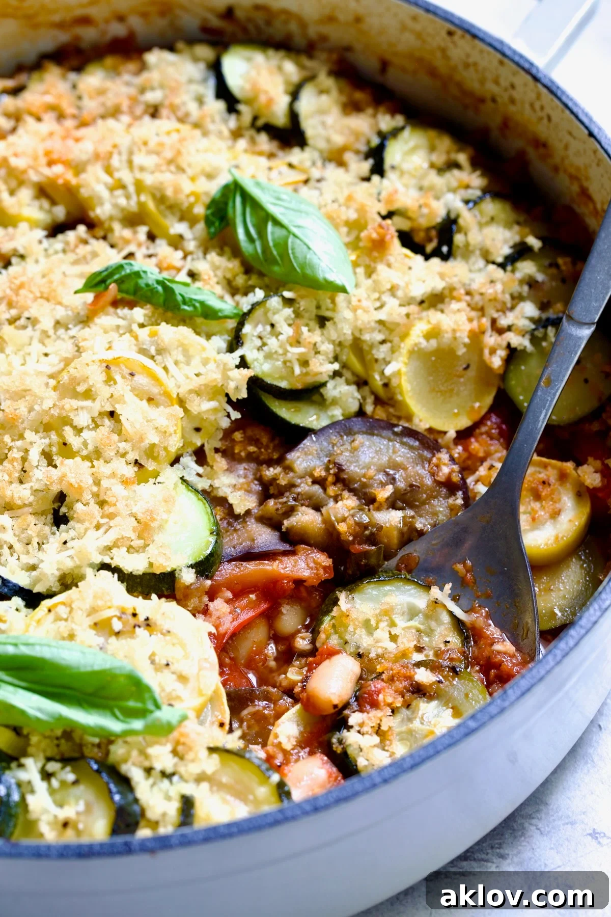 Summer Vegetable Cassoulet in white enamel cast iron skillet with serving spoon scooping some up.