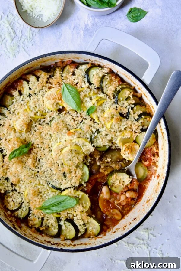 Summer Vegetable Cassoulet in white enamel cast iron skillet with serving spoon scooping some up.