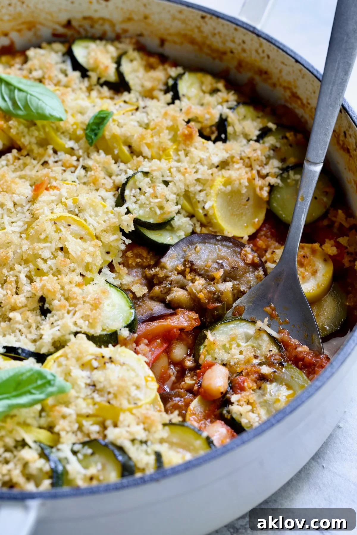 Summer Vegetable Cassoulet in white enamel cast iron skillet with serving spoon scooping some up.