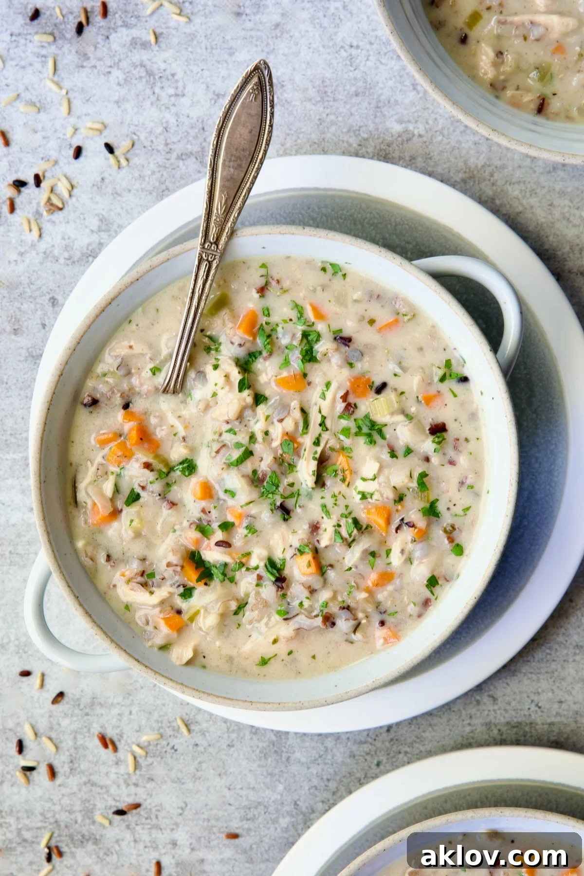 One serving of Creamy Chicken and Wild Rice Soup in white bowl with spoon.