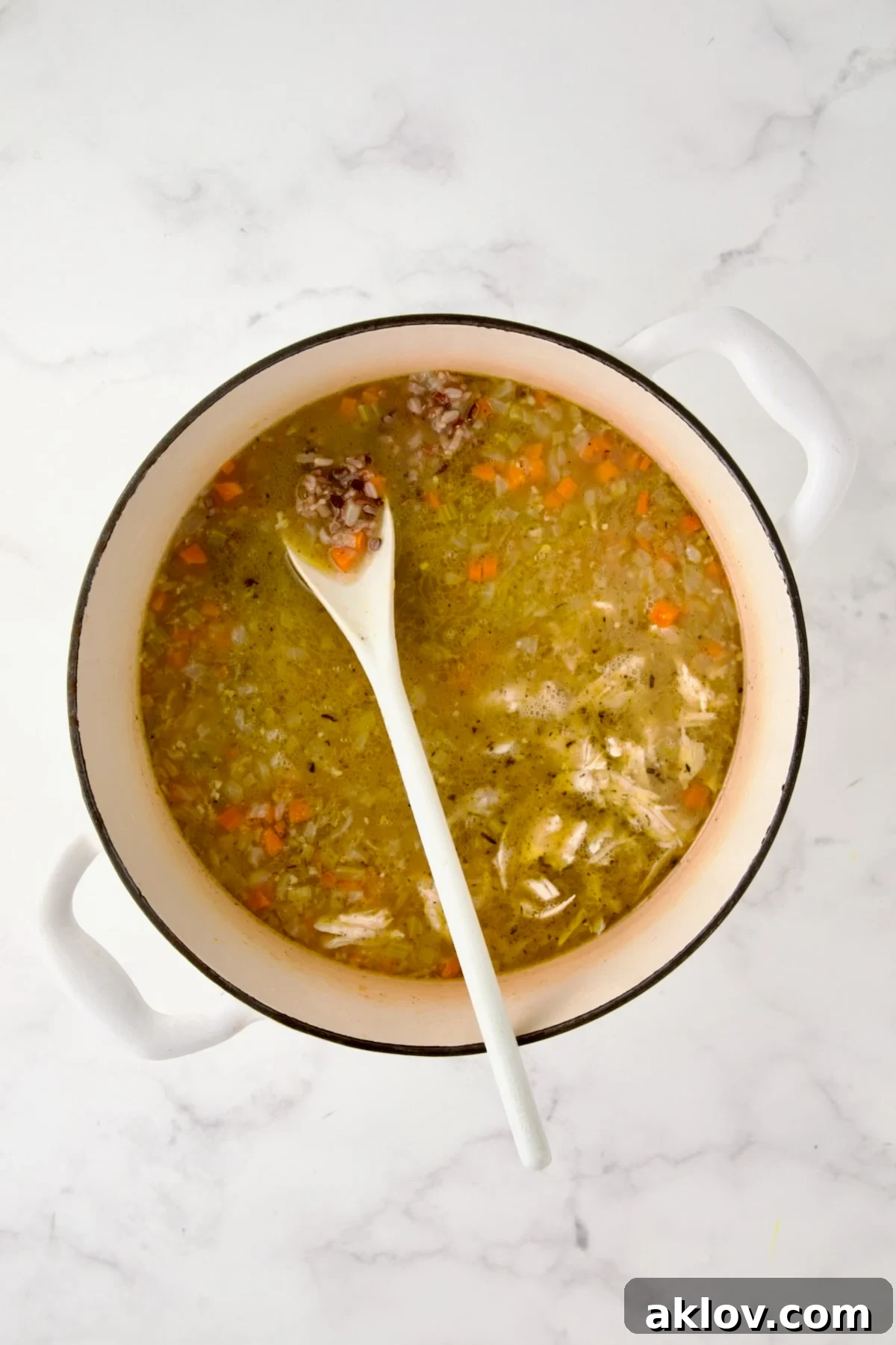 Chicken and wild rice blend added to Dutch oven with chicken broth and vegetables.