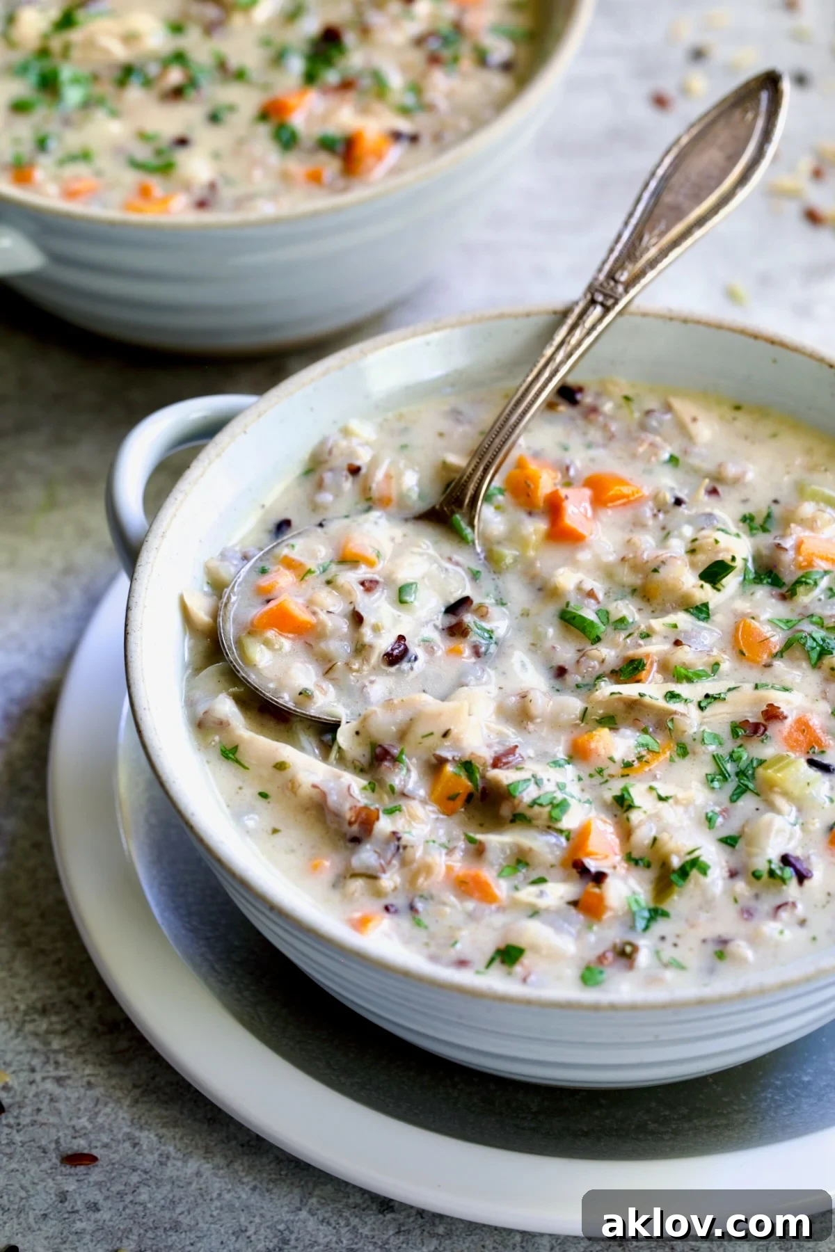 One serving of Creamy Chicken and Wild Rice Soup in white bowl with spoon.