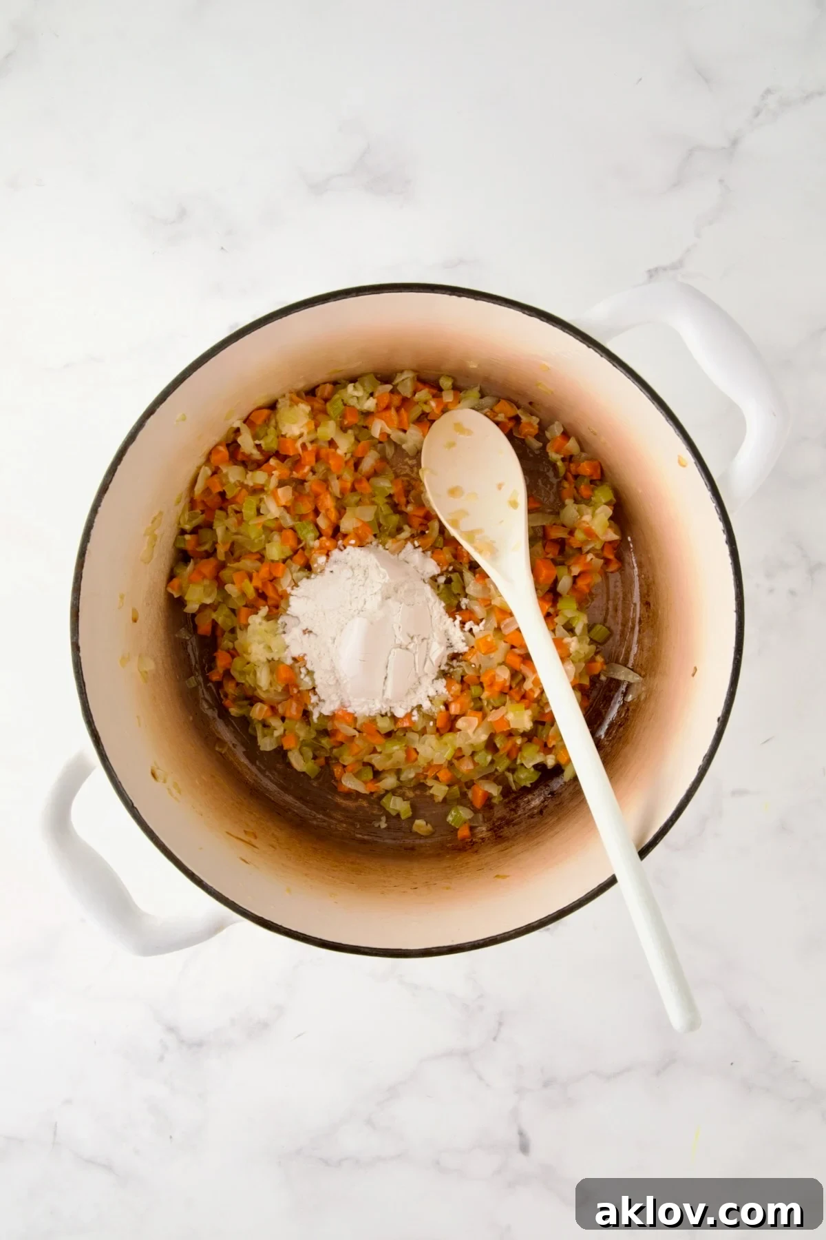Cooked onion, carrot and celery in white enamel Dutch oven with flour stirred in.