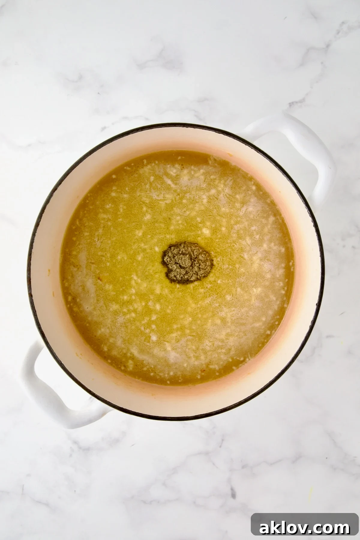 Chicken broth and poultry seasoning added to cooked onion, carrot and celery in white enamel Dutch oven.